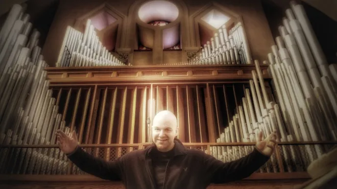 Derek Picard standing in front of the Saint Anne's pipe organ